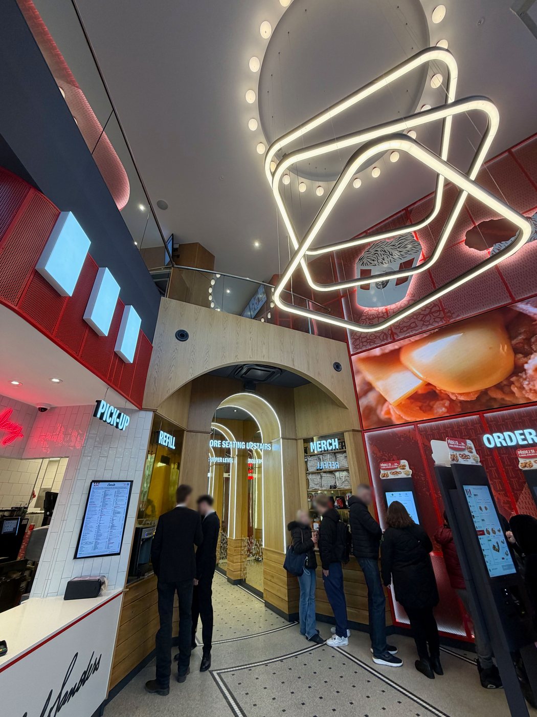 KFC VN40 — double-height atrium with suspended neon light sculpture over the order kiosks